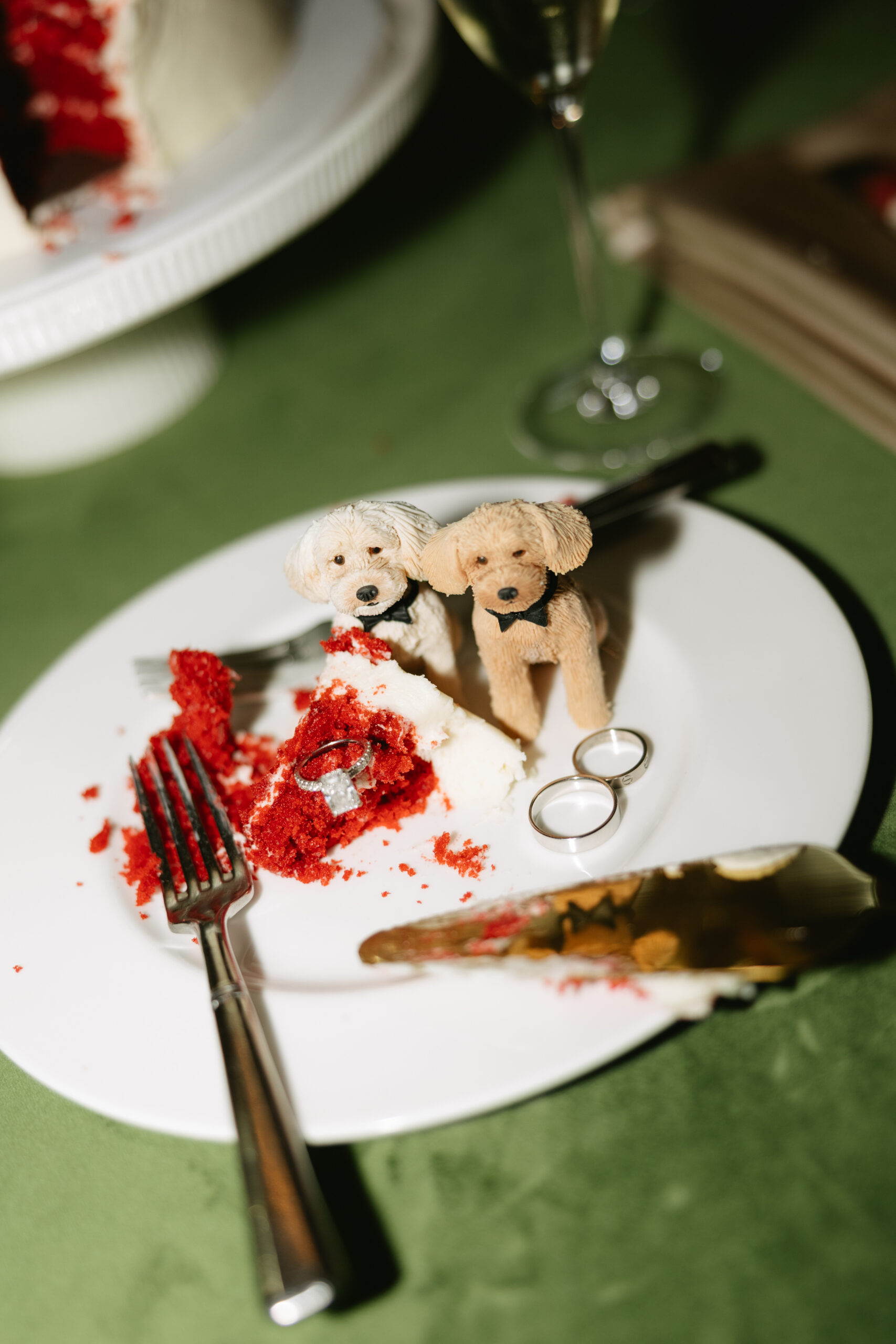 A wedding reception flatlay with cut cake and dog cake toppers