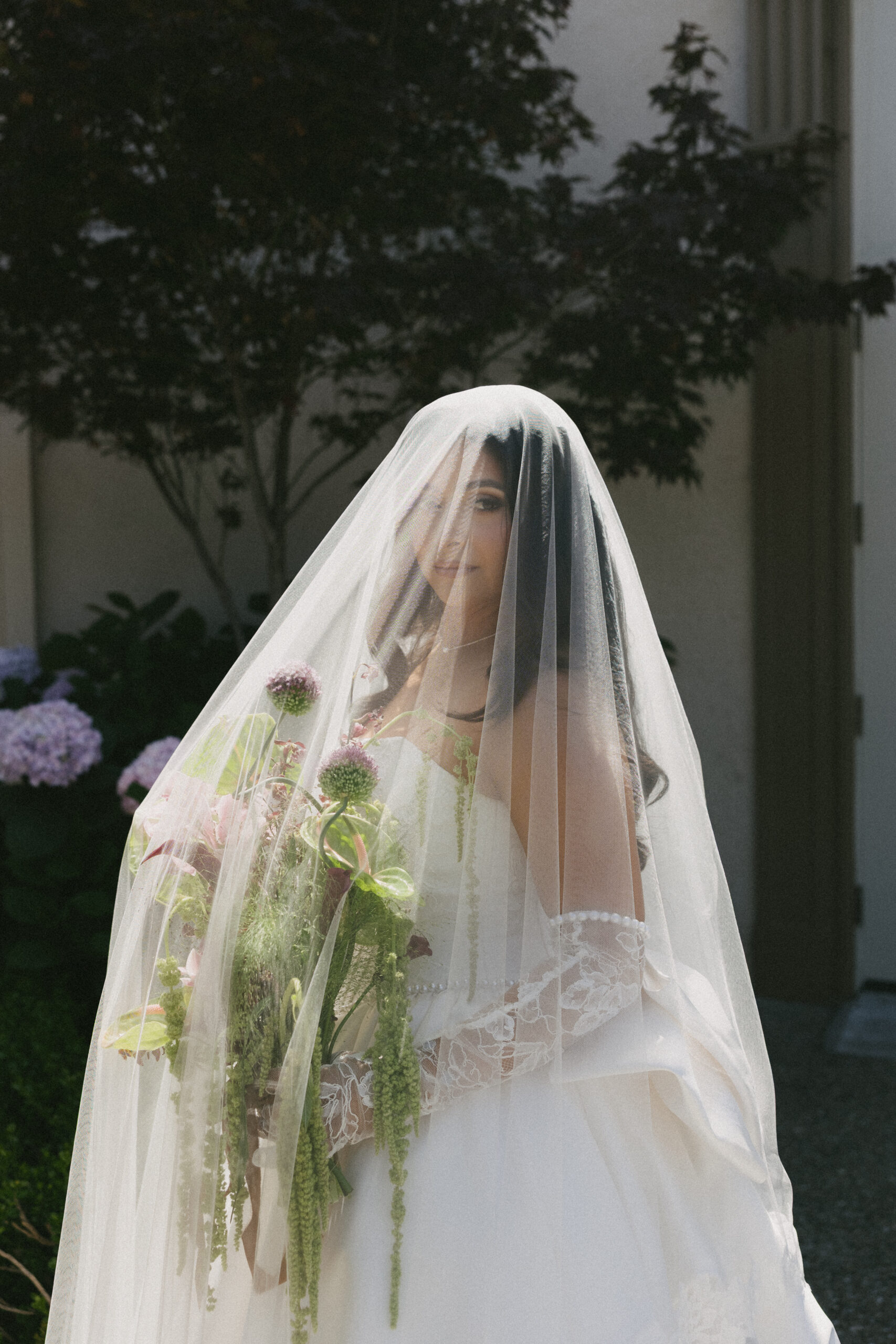 A bride posing for bridal portraits underneath her veil