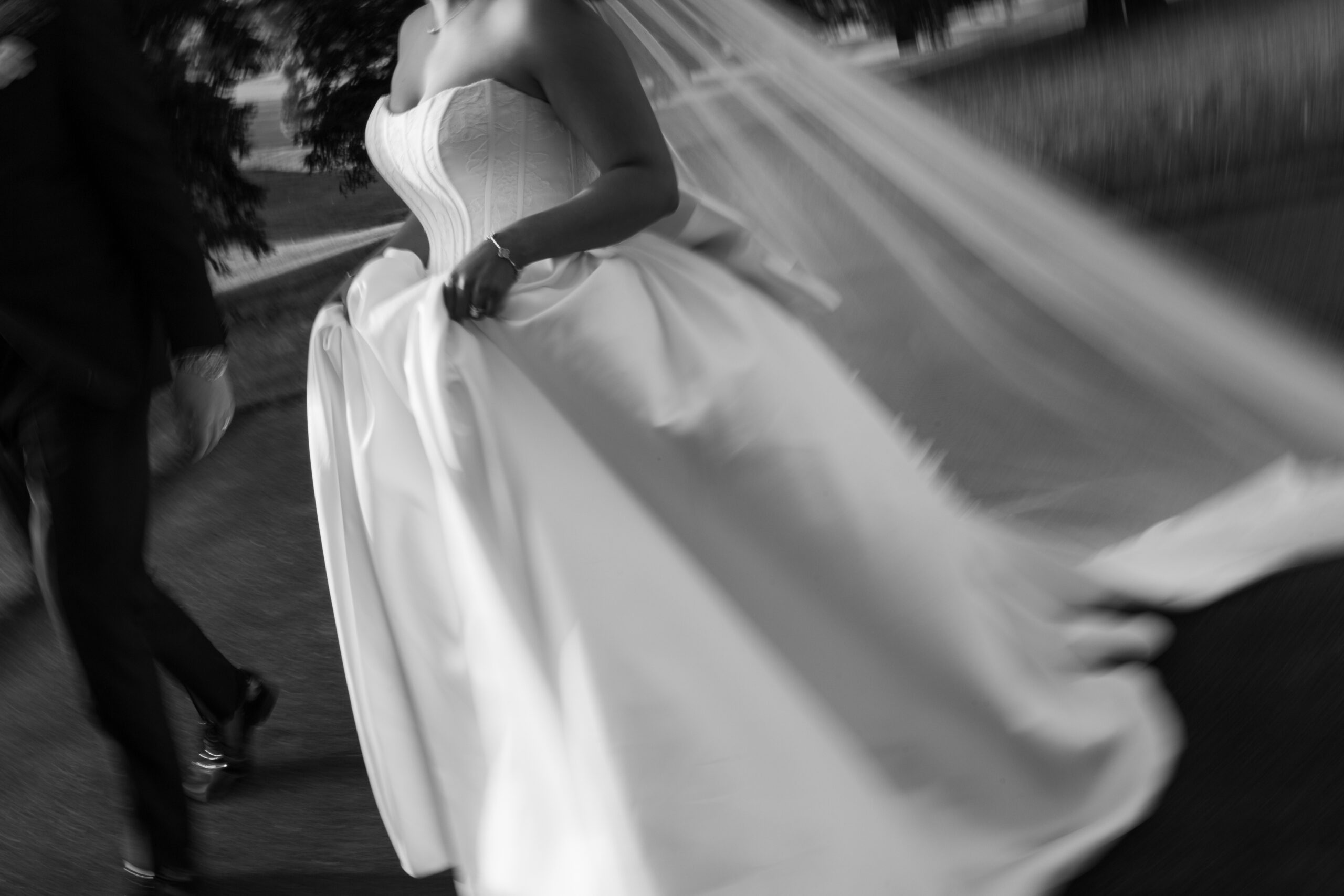 A black and white editorial wedding photo of a bride walking across Peninsula Golf and Country Club